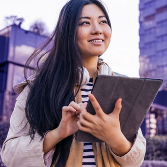 From below cheerful Asian female standing on the city street browsing on tablet looking away in sunny day; Shutterstock ID 1946550172; purchase_order: marketing advisory assurance; job: Anne; client: AI campagne
