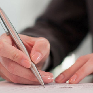 Hand schreibt mit Stift auf Papier