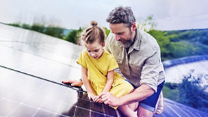 Father and daughter looking at solar panels on a rooftop