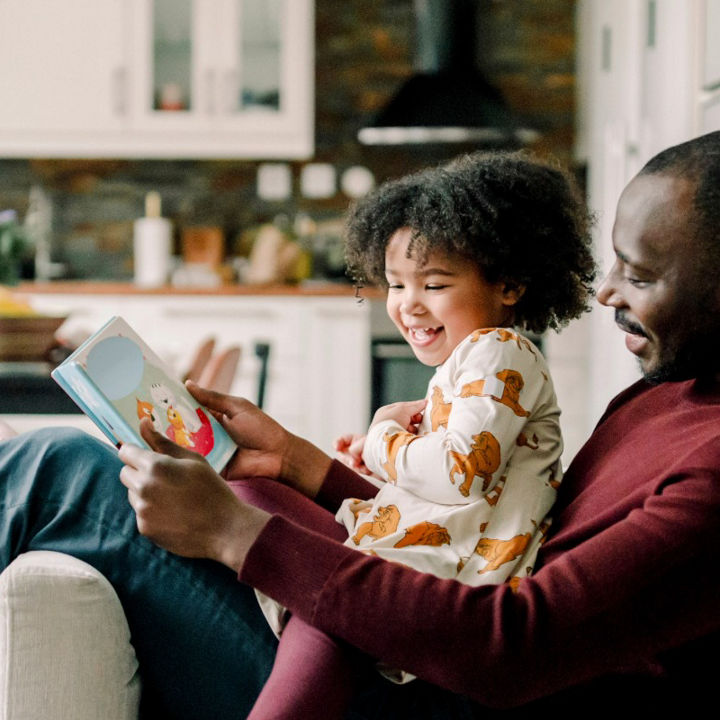 Father and daughter sat on a chair in a living room space