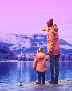 father and son standing near a lake