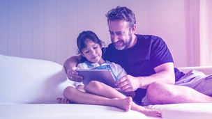 Father and daugter are watching something on an iPad ina a residential apartment