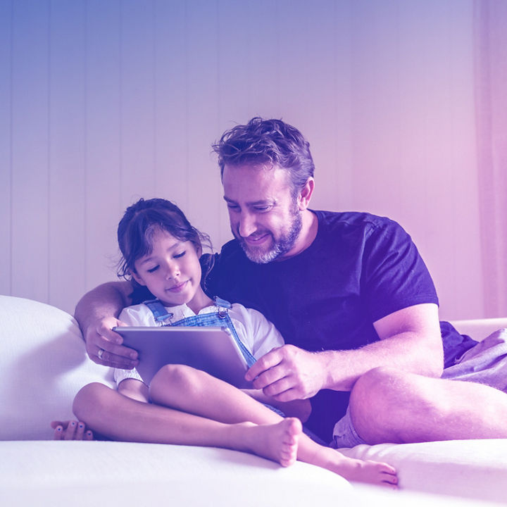 Father and daugter are watching something on an iPad ina a residential apartment