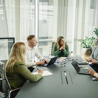 Fem ansatte sitter og diskuterer ved et motebord