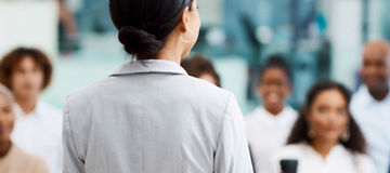 female addressing bunch of people