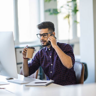 man working on monitor talking on cellphone