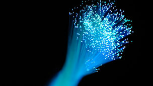 Bunch of light blue optic fibers against a black background.