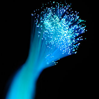 Bunch of light blue optic fibers against a black background.