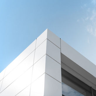 Building with white aluminum facade and aluminum panels against blue sky