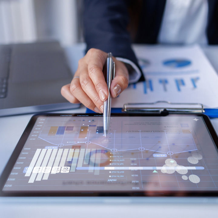 Tablet showing business analytics and charts alongside a laptop and financial documents.