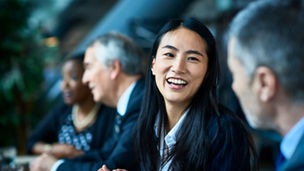 Focus on a girl laughing with the business people while sitting in a meeting