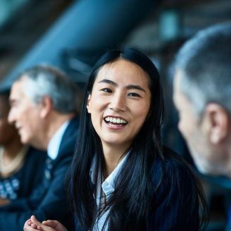 Focus on a girl laughing with the business people while sitting in a meeting