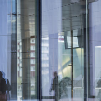 Personen laufen vor Glassgebäude