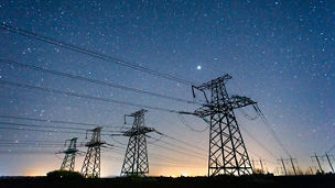 Four electric poles with night sky in background
