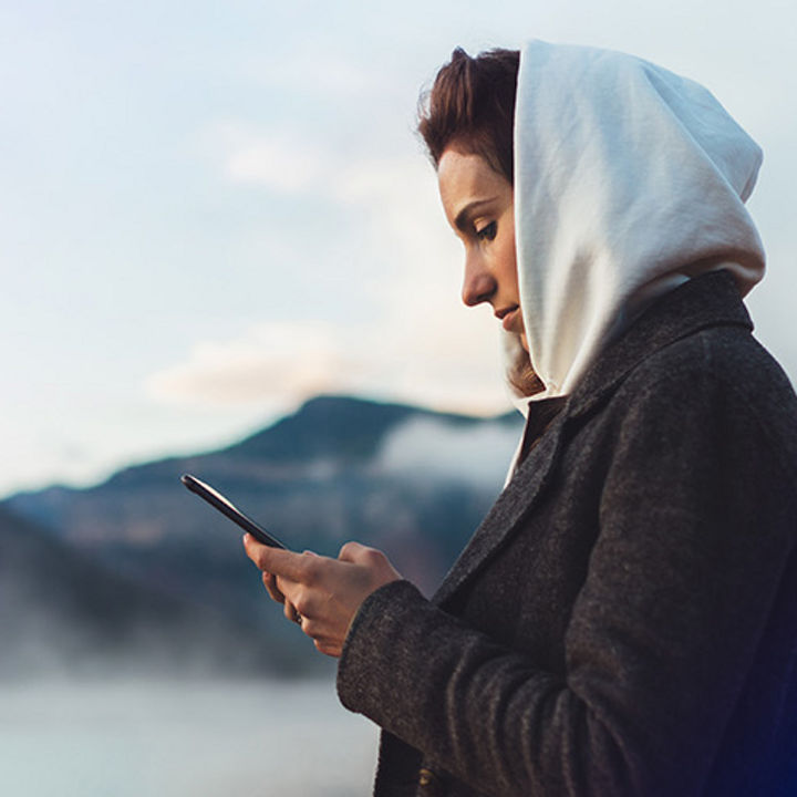 Woman with smartphone in front of mountains