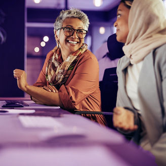 Two happy businesswomen having a discussion while working at their desks in an office. Diverse businesswomen working as a team in a creative co-working office.; Shutterstock ID 2274258875; purchase_order: advisory assurance marketing team; job: anne rouschop; client: hyperautomation