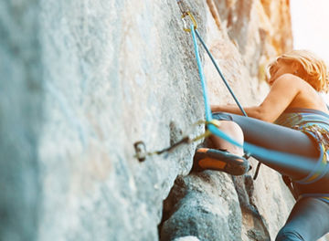 Adult female rock climber on vertical flat wall with poor relief - side view, close-up.