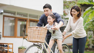 Girl riding bicycle with mother and father
