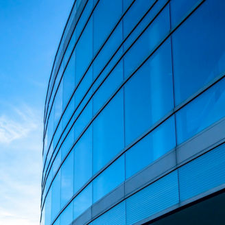 Building exterior with bright blue sky background. Building exterior with bright blue sky in the background on a sunny day. The interior of the building can be seen through the large glass windows.