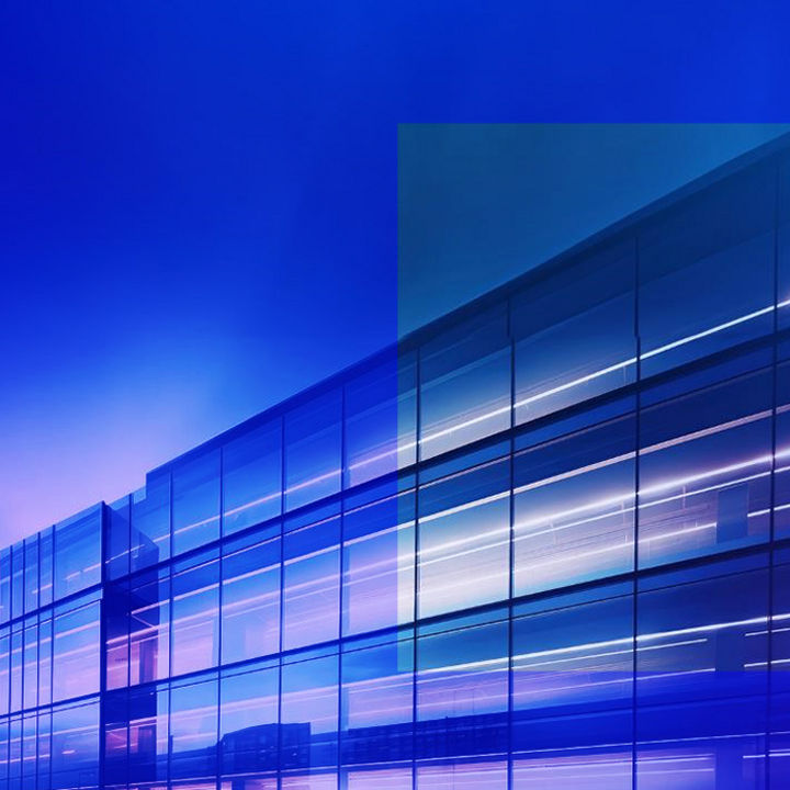 Glass building with glowing forescent lights inside banner