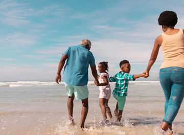 African american grandparents holding hands of grandchildren and running in sea against sky. summer, nature, copy space, unaltered, family, love, togetherness, childhood, enjoyment, holiday.