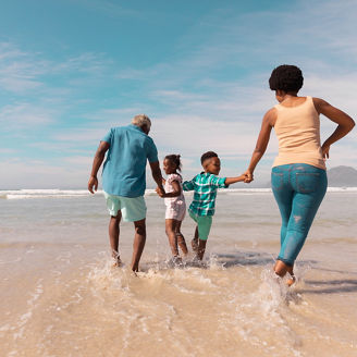 African american grandparents holding hands of grandchildren and running in sea against sky. summer, nature, copy space, unaltered, family, love, togetherness, childhood, enjoyment, holiday.