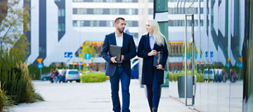 Elegant and confident young businesswoman and businessman walking the city, in the financial district. 
