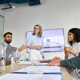 Diverse executive team people discussing company strategy at board meeting. Multicultural employees with senior leader listening indian manager brainstorming working sitting at table in office.