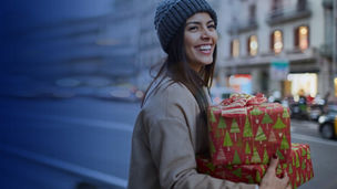 lady in winder clothing holding christmas gifts