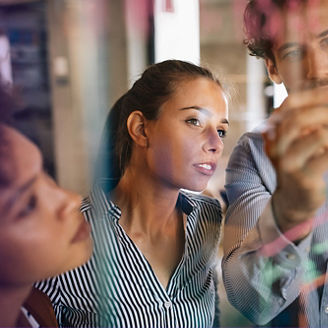 one man and two women co-workers planning using a transparent blackboard