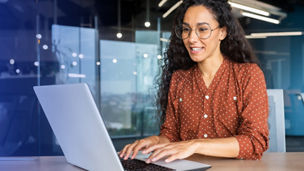 woman with dark orange shirt working on her laptop
