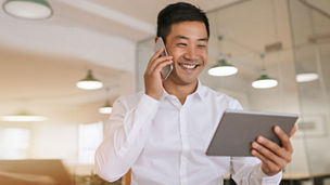 Man talking on phone while holding a tablet