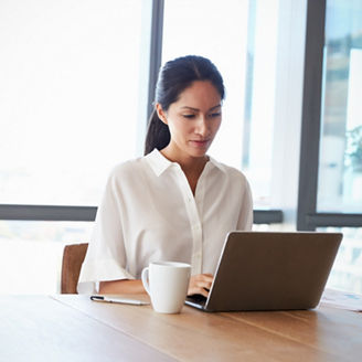 Businesswoman Working Alone On Laptop In Office Boardroom