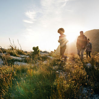 Group of friends are hiking in mountain on a sunny day. Young people walking through countryside.