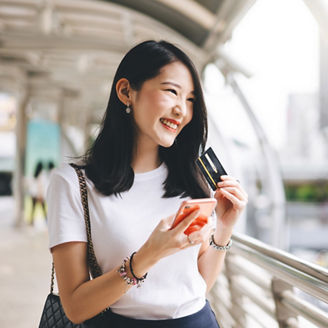 Business people shopping via online application media concept. Happy smile young adult asian woman consumer using creadit card and smartphone. City on day background with copy space.