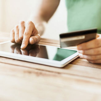 Young man using credit card with digital tablet at home