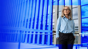 Person in blue shirt standing in front of glass building