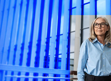 Person in blue shirt standing in front of glass building