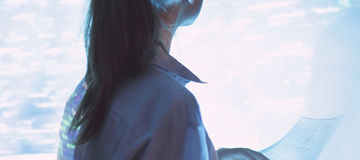 Mujer de espaldas con lentes viendo una pantalla