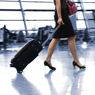Woman in heels and skirt walking through airport with luggage 