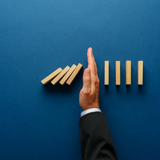 Top view  of businessman hand stopping falling dominos in a business crisis management conceptual image.