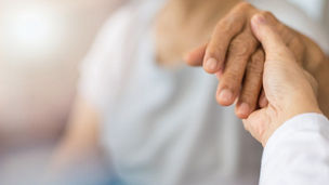 Geriatric doctor or geriatrician concept. Doctor physician hand on happy elderly senior patient to comfort in hospital examination room or hospice nursing home or wellbeing county. 