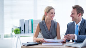 Happy colleagues working together on laptop and folder in the office