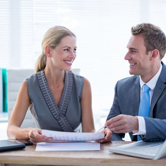 Happy colleagues working together on laptop and folder in the office