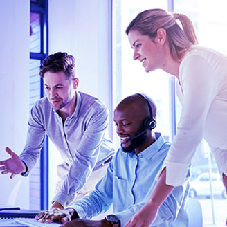 Três colegas a conversar sorrindo olhando para um ecrã