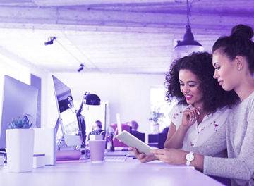 Dos compañeras de trabajo revisando un dispositivo inteligente