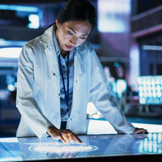 Female Asian Neuroscinetist Using Interactive Touch Screen Table With MRI Scans On Display In Modern Biotechnology Research Center. Doctor Developing Innovative Devices For People With Brain Damage.