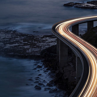 Highway mit Lichtspur der Autos am Meer