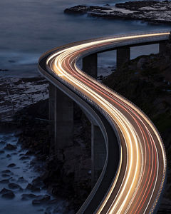 Highway mit Lichtspur der Autos am Meer