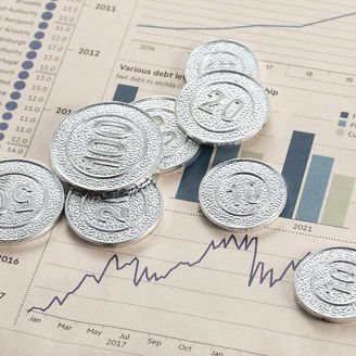 A high angle shot of silver coins on pages with bar graphs